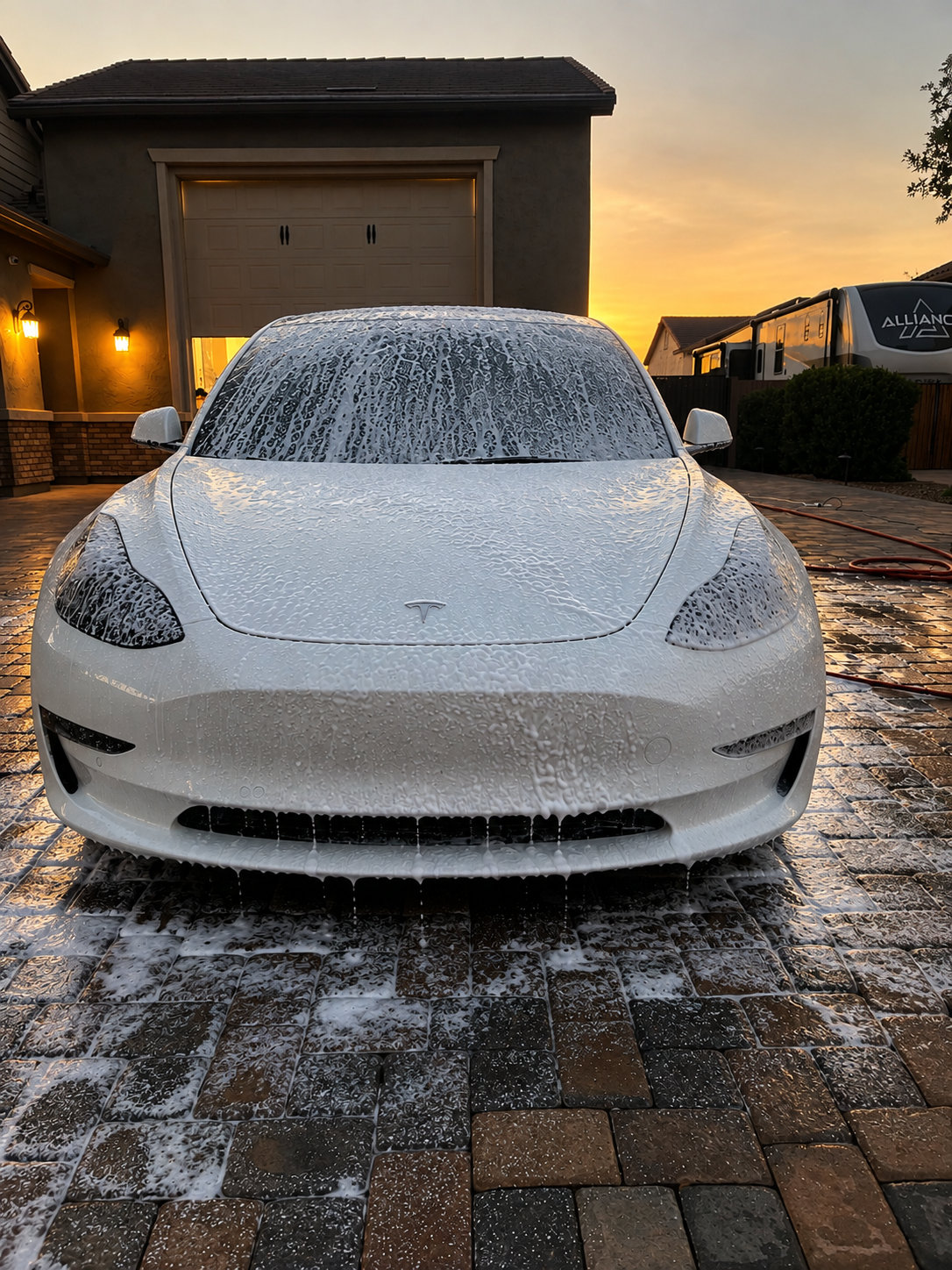 White sedan covered in thick snow foam during an exterior detail